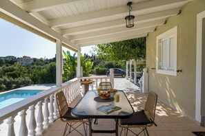 A covered outdoor area with a pool, dining table, chairs, and a view of the surrounding landscape. - Green retreat ,family friendly , sea view, privacy, picturesque village (spartia)