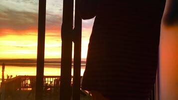A person standing by a window overlooking a sunset.