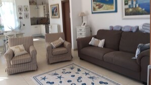 Una sala de estar con sillones a rayas, un sofá marrón y una alfombra estampada.