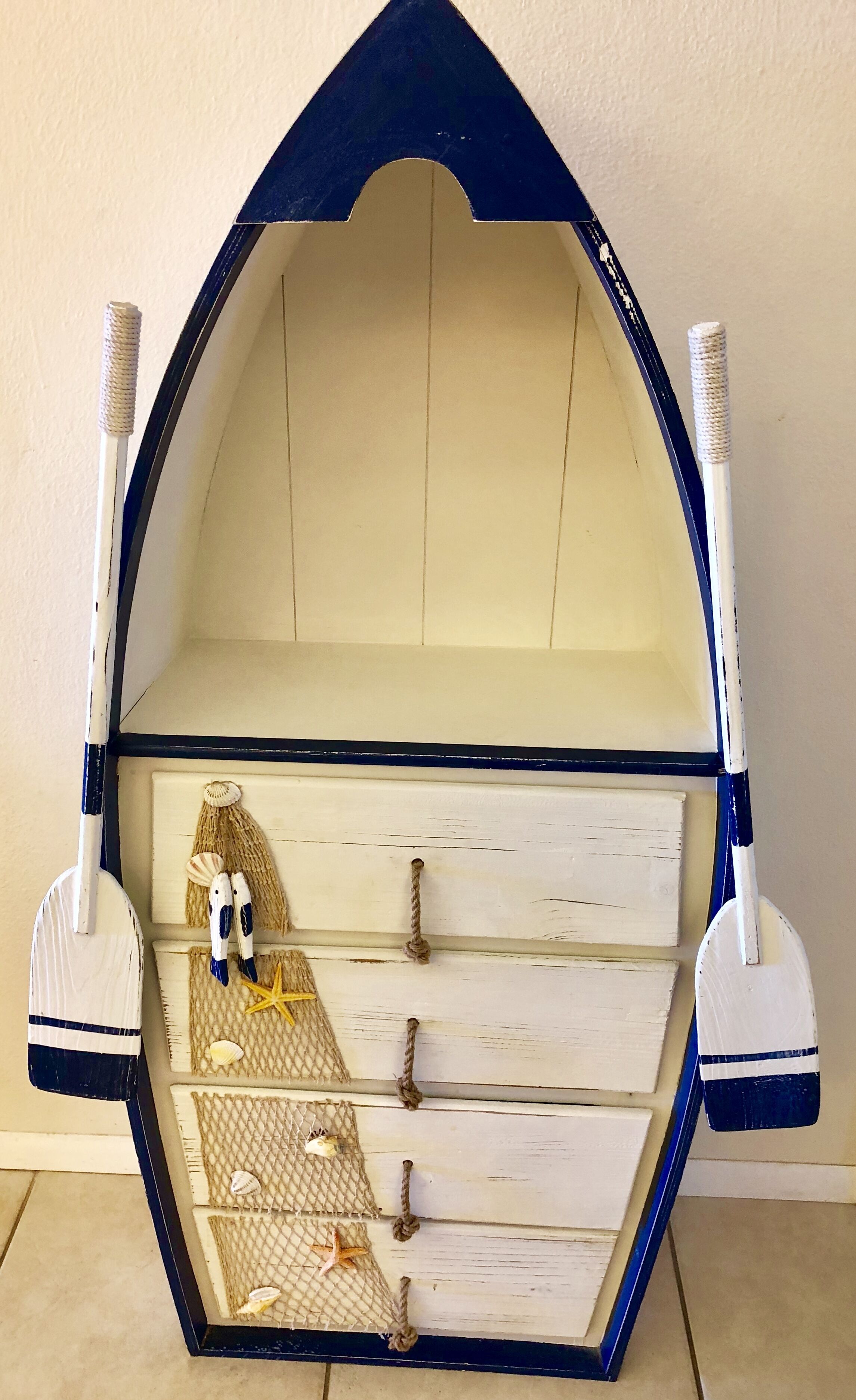 A nautical-themed shelf with a blue and white color scheme, featuring a starfish, seashells, and a rope.