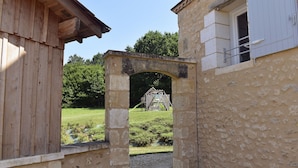 Un arco in pietra conduce a un edificio in legno con una finestra.