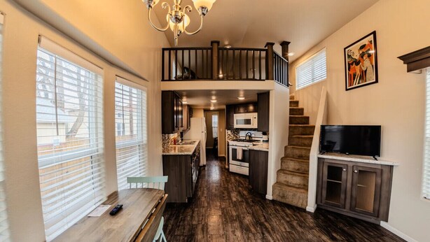 A spacious kitchen with a dining area, a staircase, and a TV. - Pet-Friendly Tiny Home Near Arches | Sleeps 6 | Fenced Yard | Sunset Mesa (Moab)