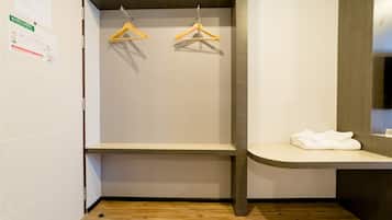 A small, modern bathroom with a wooden floor, a bench, and two wooden hangers on a wall.