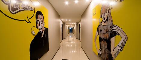 Un pasillo con paredes amarillas y piso pulido, con un gran cuadro mural de un hombre y una mujer.