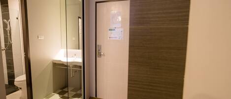 Un baño moderno con cabina de ducha de vidrio, lavamanos blanco y piso de madera.