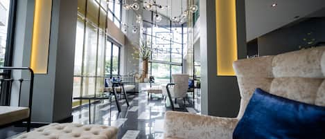 Eine großzügige Lobby mit hoher Decke, moderner Beleuchtung und Blick ins Freie durch große Fenster.