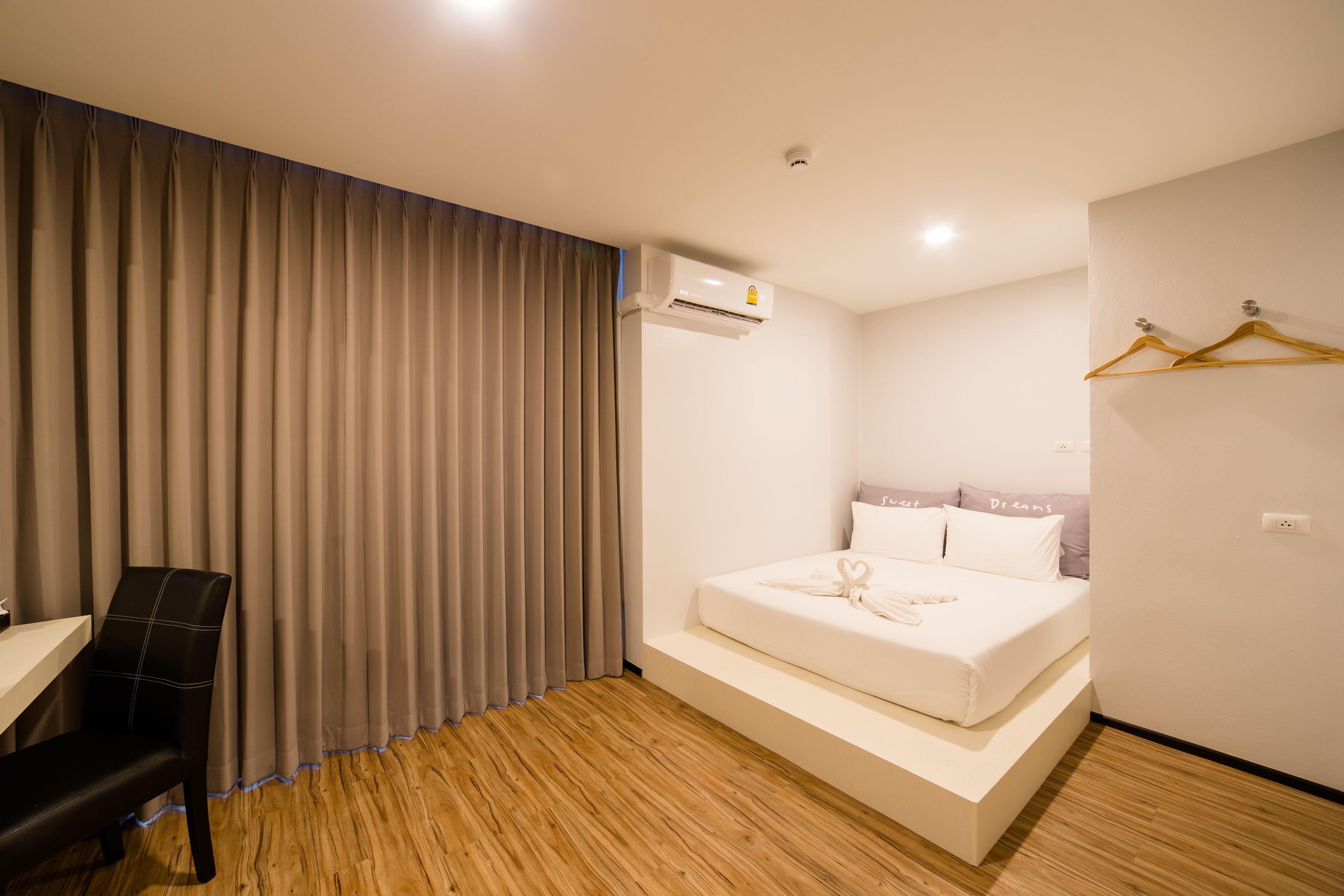 A modern hotel room with a bed, a desk, and a chair.