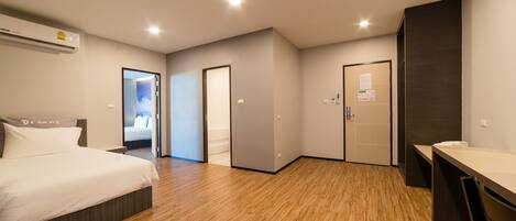 Una habitación de hotel moderna con piso de madera, una cama, un escritorio y un baño.