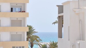 Un edificio de varios pisos con balcones que dan a una playa.