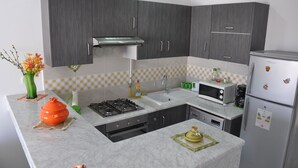 Una cocina moderna con armarios grises, estufa a gas, microondas y refrigerador.