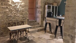 Una cocina rústica con paredes de piedra, una mesa de madera y taburetes de bar.