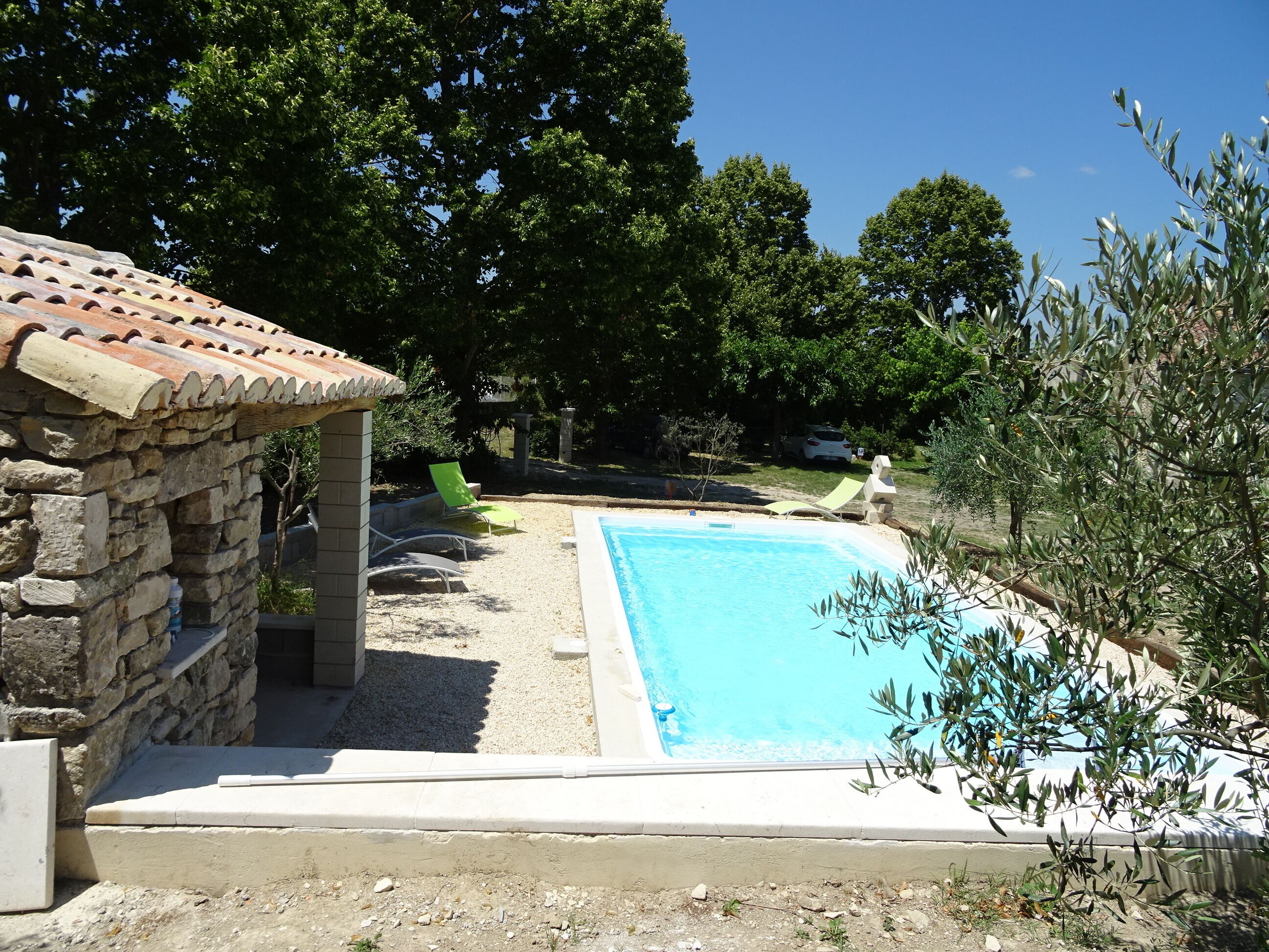 A swimming pool with a stone structure and a tiled roof nearby.