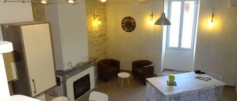 A dining area with a white table and chairs, a fireplace, and a clock on the wall.