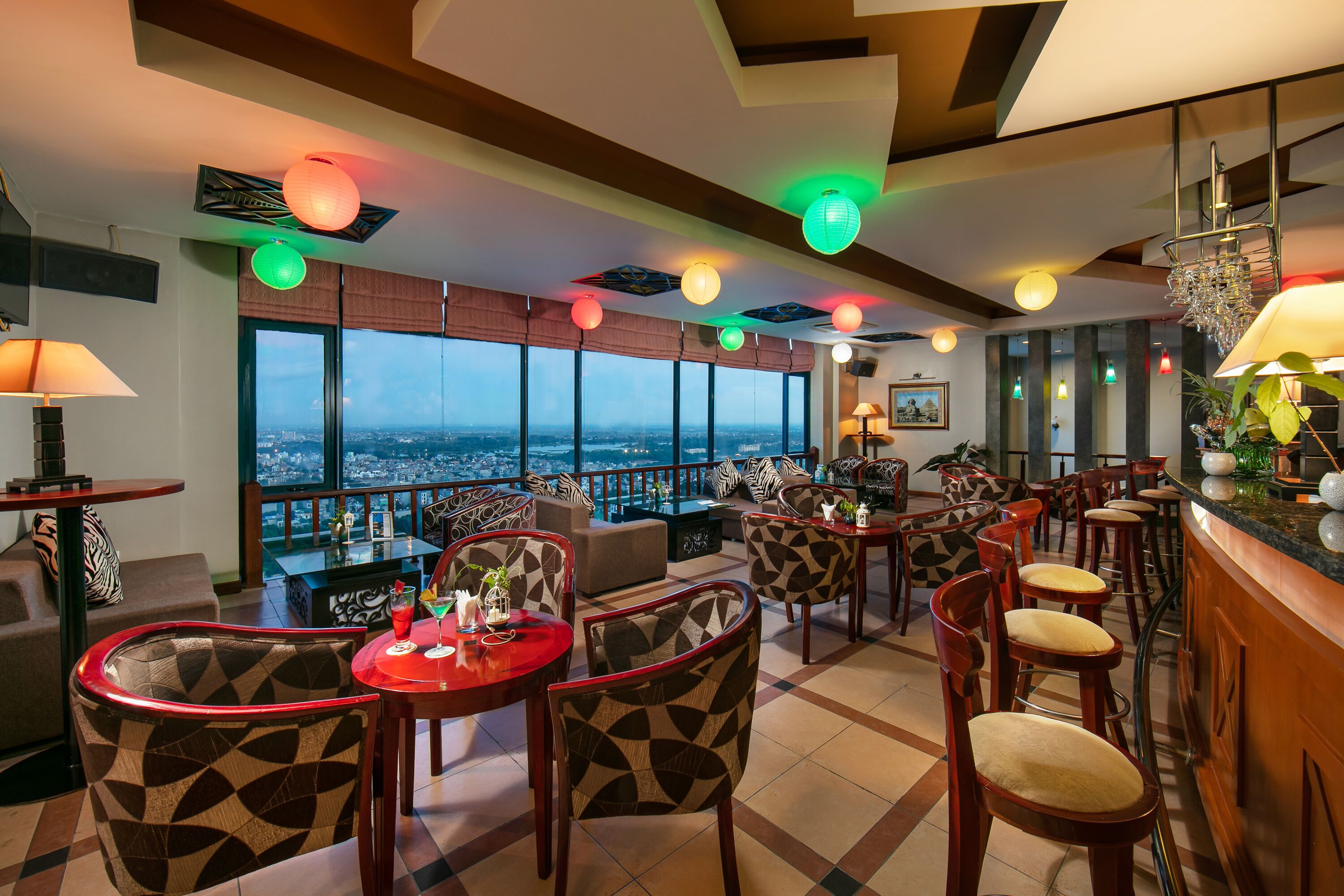 Eine Bar in einem Hochhaus mit weitreichendem Stadtblick, Sitzgelegenheiten mit Musterung und stimmungsvoller Beleuchtung.
