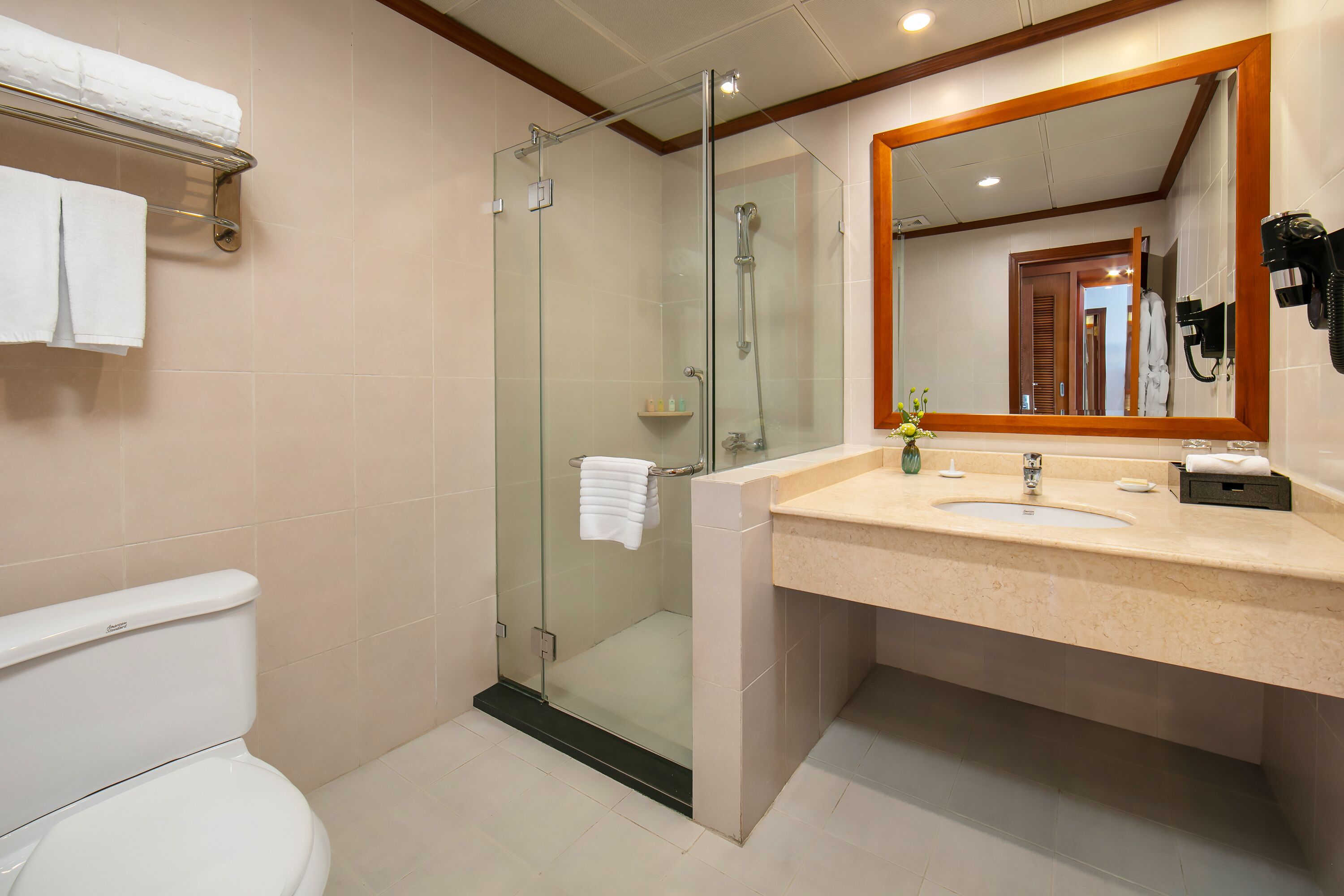 Un bany modern amb dutxa envidriada, vàter, un lavabo amb mirall i un suport per a tovalloles.