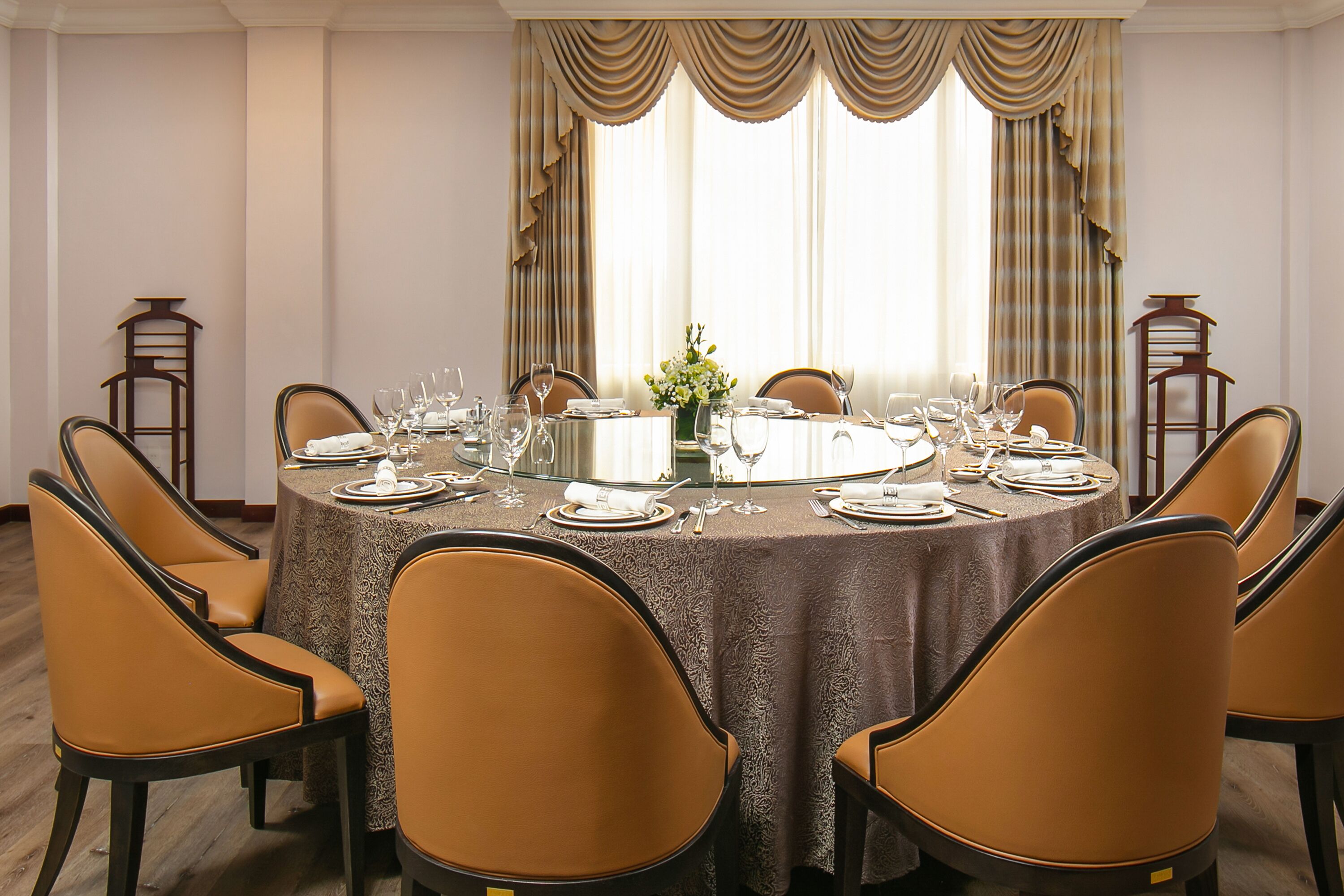 Comedor con mesa redonda dispuesta para seis comensales, rodeada por seis sillas, y un jarrón de flores sobre la mesa.