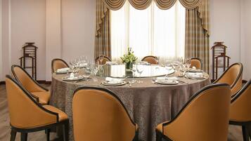 Comedor con mesa redonda dispuesta para seis comensales, rodeada por seis sillas, y un jarrón de flores sobre la mesa.