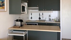Une cuisine moderne avec des meubles de couleur sombre, un four à micro-ondes, un évier et une machine à café.
