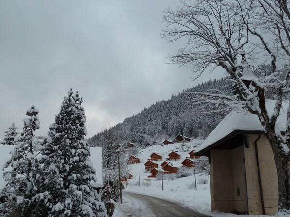 Schneebedeckte Landschaft mit einer Straße, die zu einer Reihe Holzhütten führt.