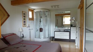 Ein Schlafzimmer mit Bett, Nachttisch, Lampe und einer Duschkabine.