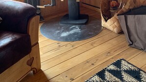 Ein gemütlicher Raum mit Kaminofen, Holzwänden, einer Ledersofa und einem Teppich.