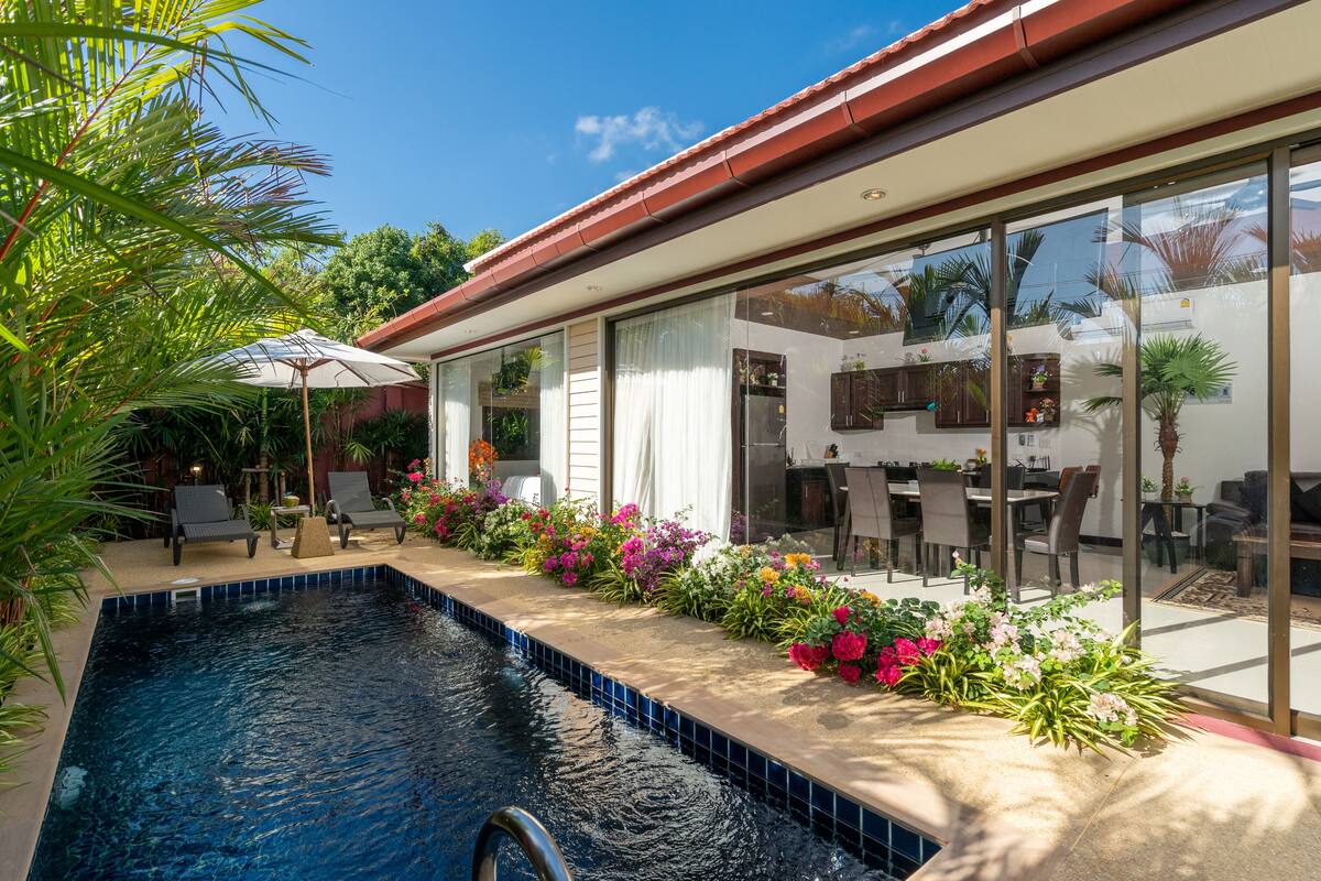 A modern house with a swimming pool, outdoor furniture, and a patio area with plants.
