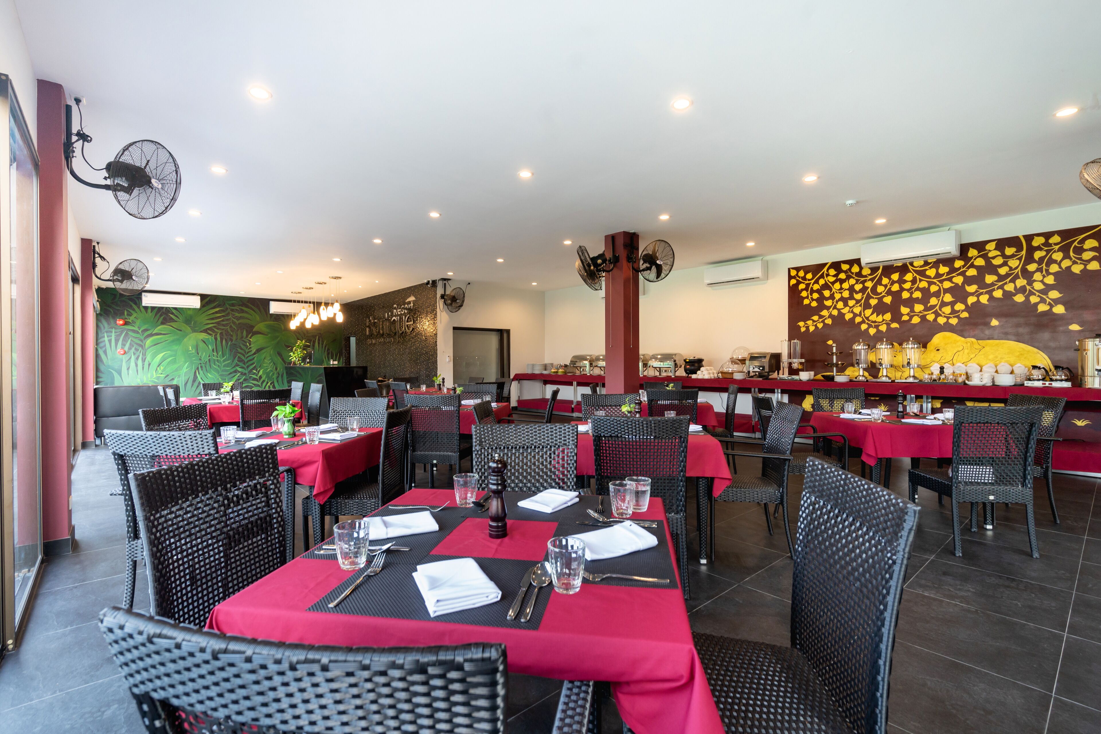 Ein Restaurant mit mehreren Tischen und Stühlen, jeweils gedeckt mit Besteck und Gläsern.