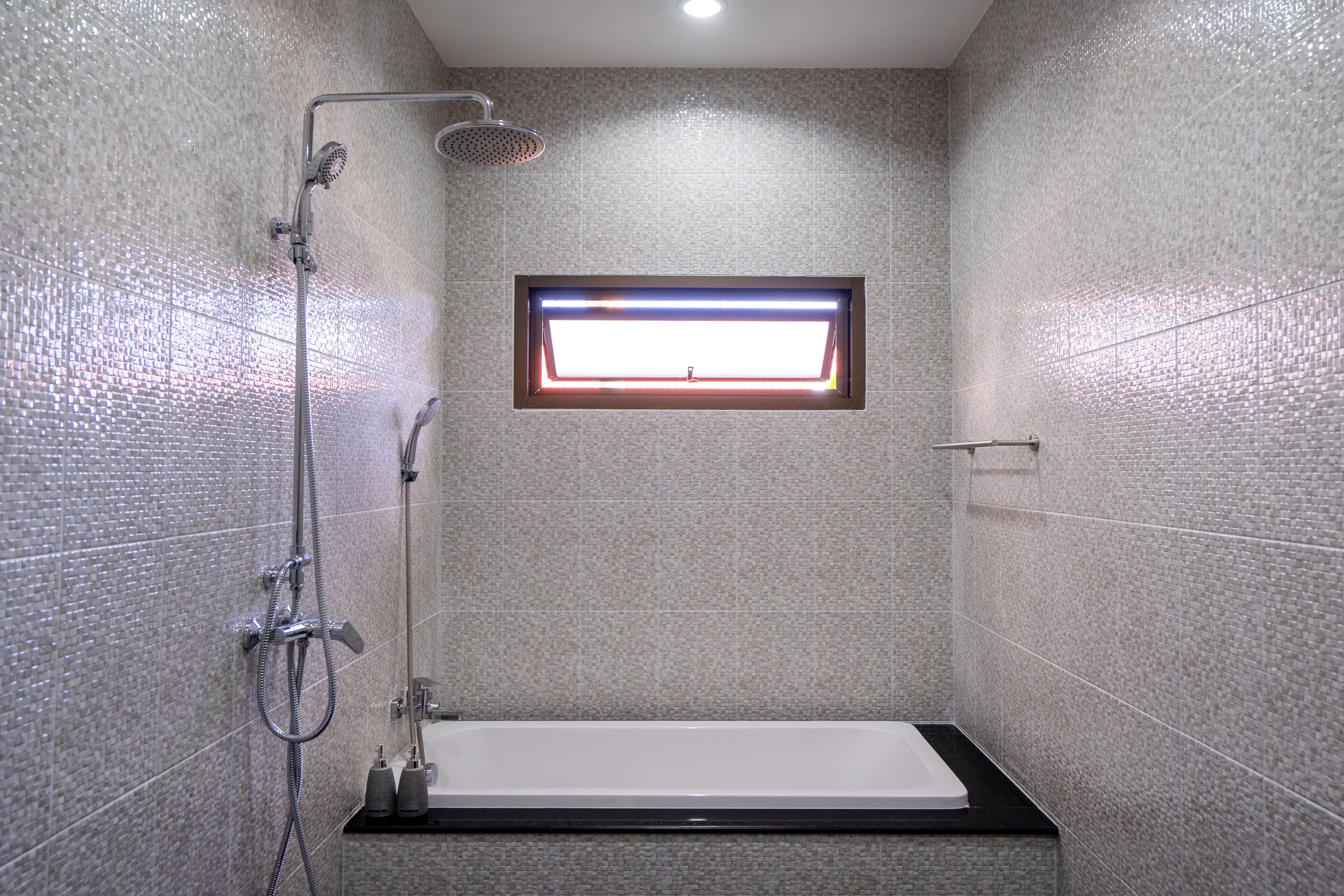 Une salle de bain moderne avec une douche, une fenêtre et une baignoire.