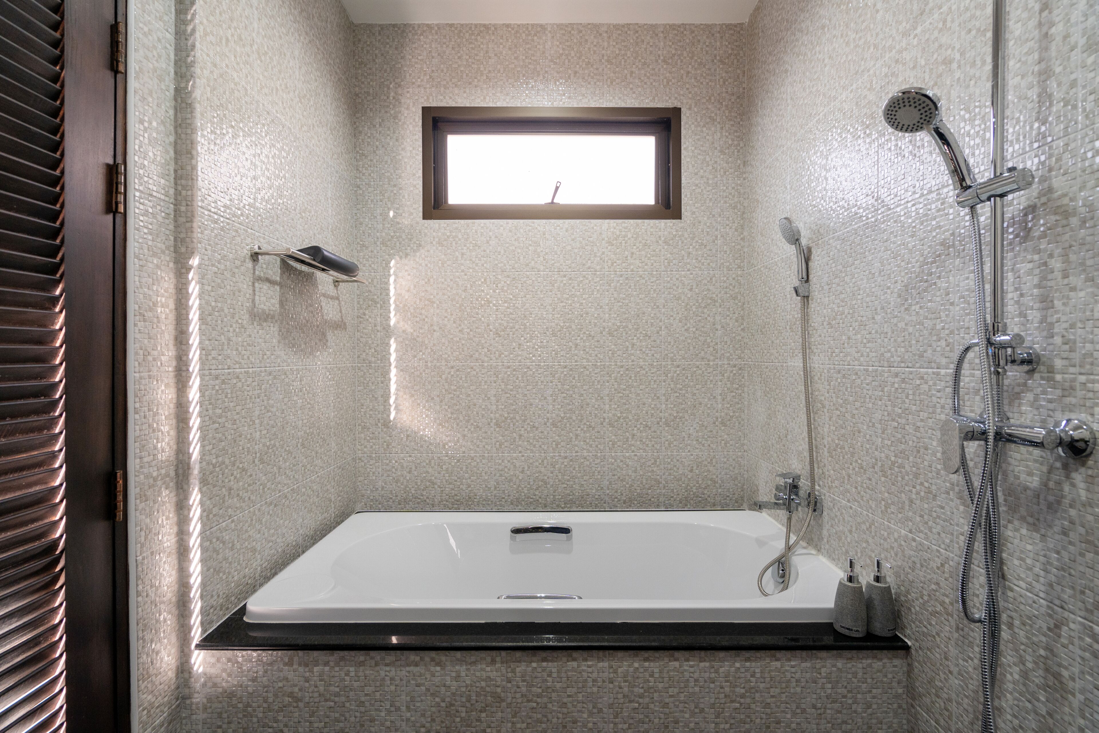 Un baño moderno con una bañera grande, ducha y una ventana pequeña.