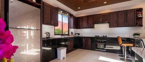 Una cocina moderna con armarios de madera oscura, un refrigerador de acero inoxidable y una encimera negra.