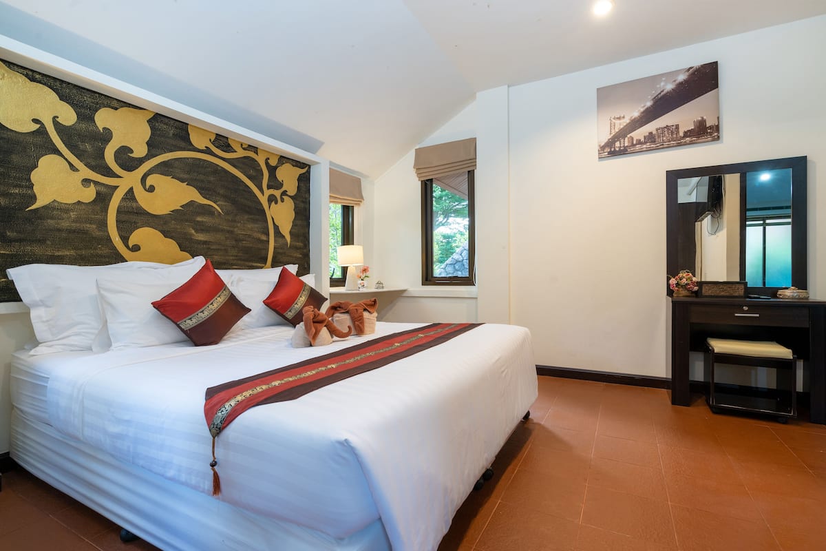 A hotel room with a large bed, a desk, a mirror, and a cityscape picture on the wall.
