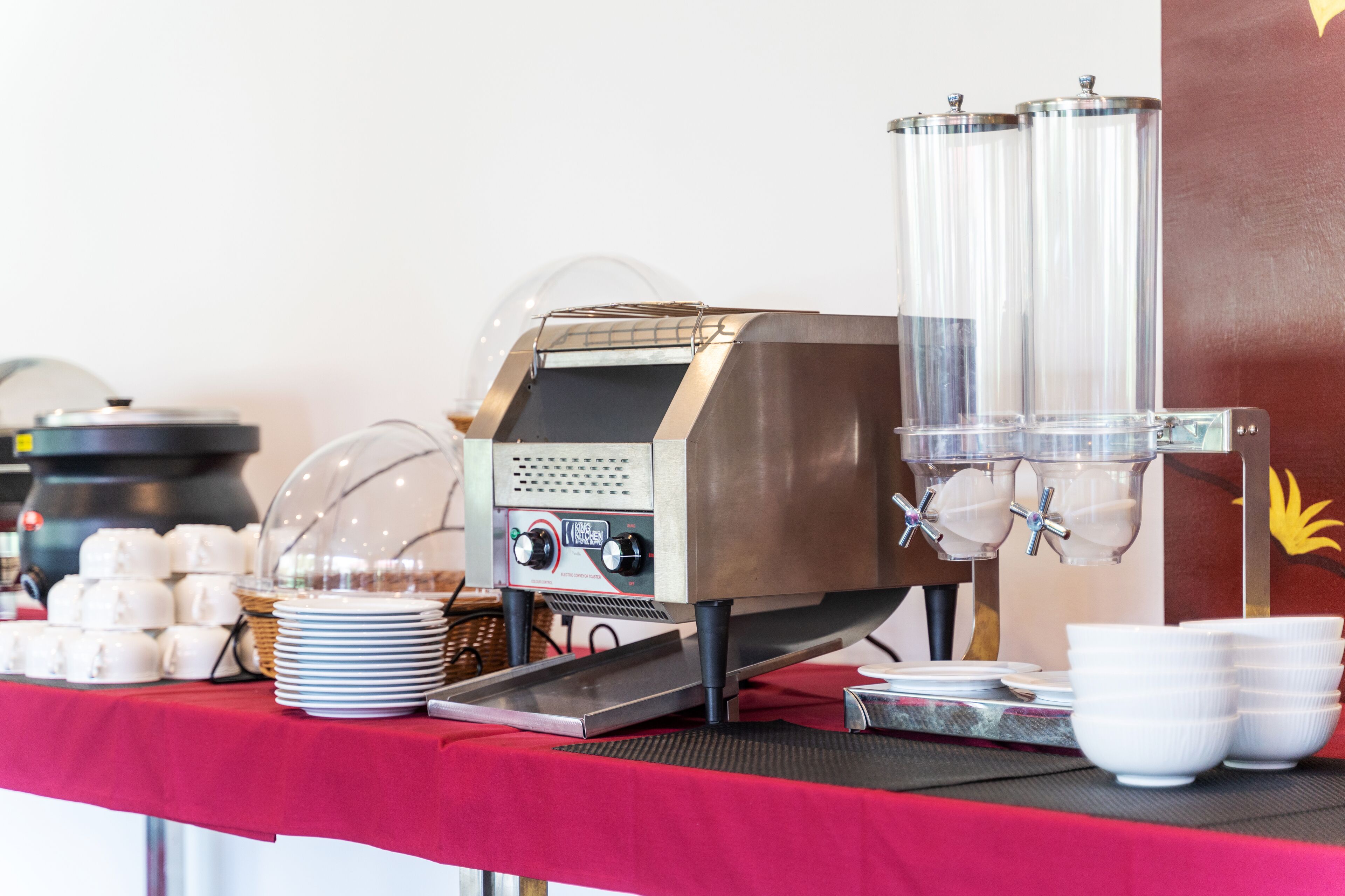A buffet setup with a coffee machine, serving trays, and stacked bowls.
