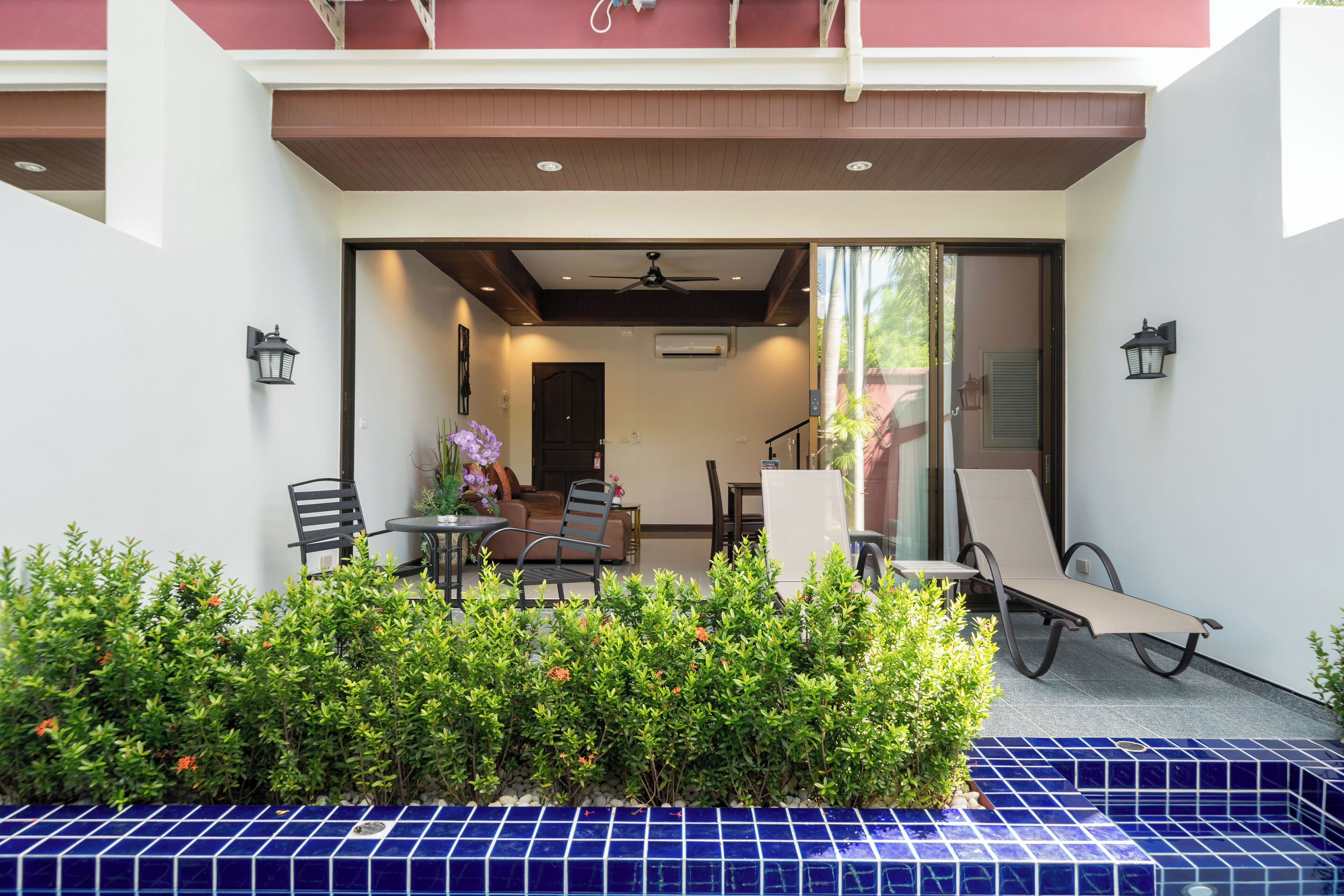 A covered outdoor seating area with a table, chairs, and a lounge chair.