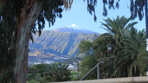 A stone wall with a view of a mountain and a town in the background. - Apartment with fantastic panoramic views to the Teide and the sea, balcony facing west (Puerto de la Cruz)