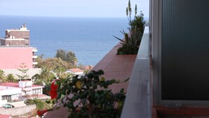 A balcony with a view of the sea, a building with a red roof, and some greenery. - Apartment with fantastic panoramic views to the Teide and the sea, balcony facing west (Puerto de la Cruz)