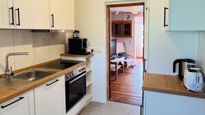 Eine kleine Küche mit weißen Schränken, einer Holz Arbeitsplatte, einem eingebauten Backofen und einer Kaffeemaschine.