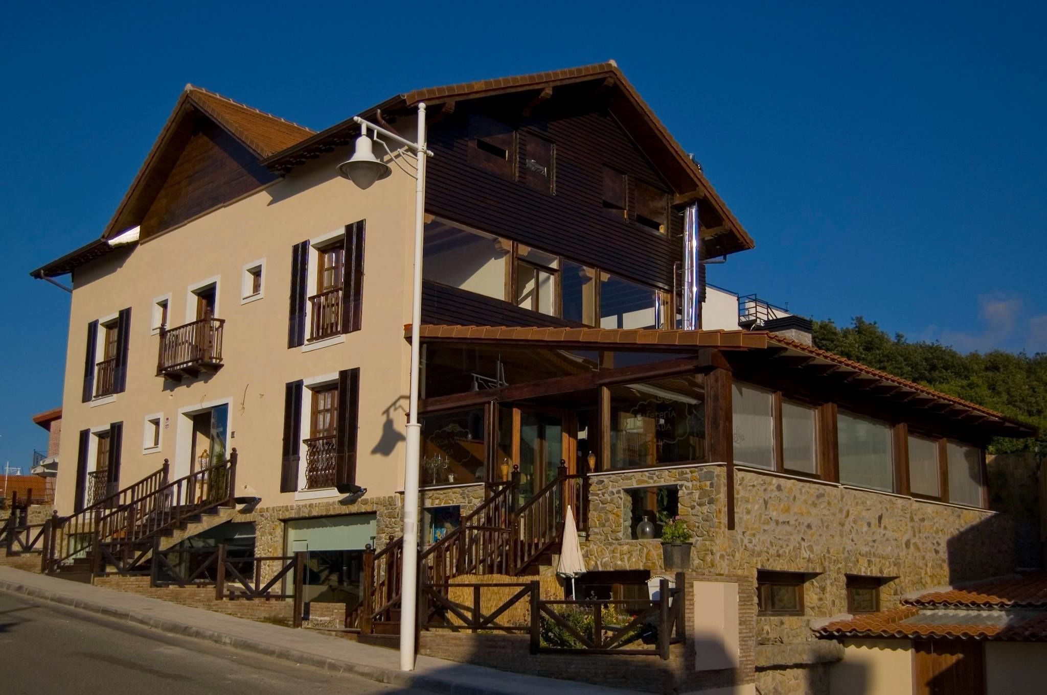 A multi-story building with a stone facade, wooden balconies, and a staircase leading to the entrance.