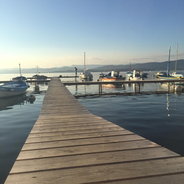 Une jetée en bois qui mène à une marina où sont amarrés des bateaux.