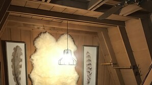 Un dormitorio estilo loft con techo inclinado, una cama con edredón estampado, dos mesitas de noche y un cuadro de plumas en la pared.