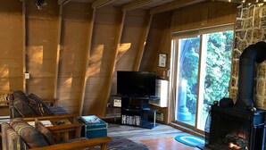 Un salón acogedor tipo loft con vigas de madera, una chimenea, un sofá y un televisor.