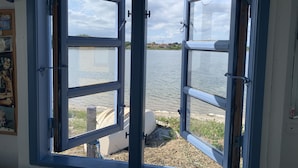 Ein Zimmer mit großem Fenster und Blick auf ein Gewässer.
