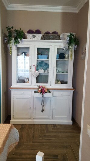 A white cabinet with glass doors, adorned with decorative items and a floral arrangement.