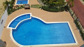 Ein großer, gewölbter Swimmingpool mit einer gefliesten Sonnenterrasse darum.