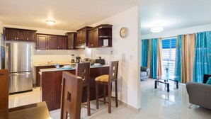 Eine moderne Küche mit einem Edelstahlkühlschrank, Holzschränken und einem Essbereich mit Tisch und Stühlen.