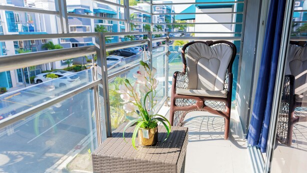 Ein Balkon mit einem Korbstuhl, einem Tisch und einem Blumentopf.