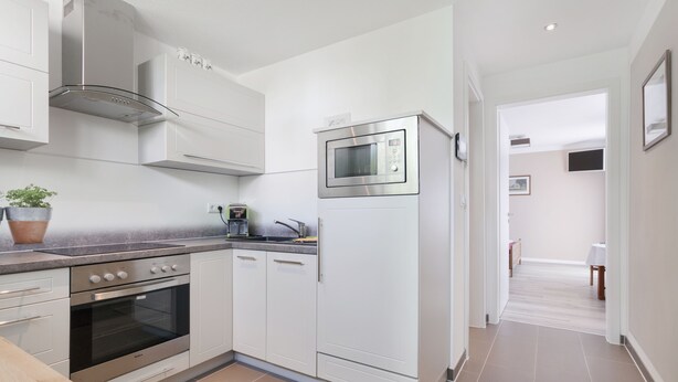 A modern kitchen with stainless steel appliances, white cabinetry, and a tiled floor. - Typically Saxon! Cozy little apartment in the heart of Dresden. (Dresden)
