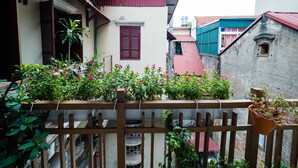 A courtyard with a wooden fence, potted plants, and buildings with red and blue roofs. - Hanoi Balcony Homestay (Hanoi)