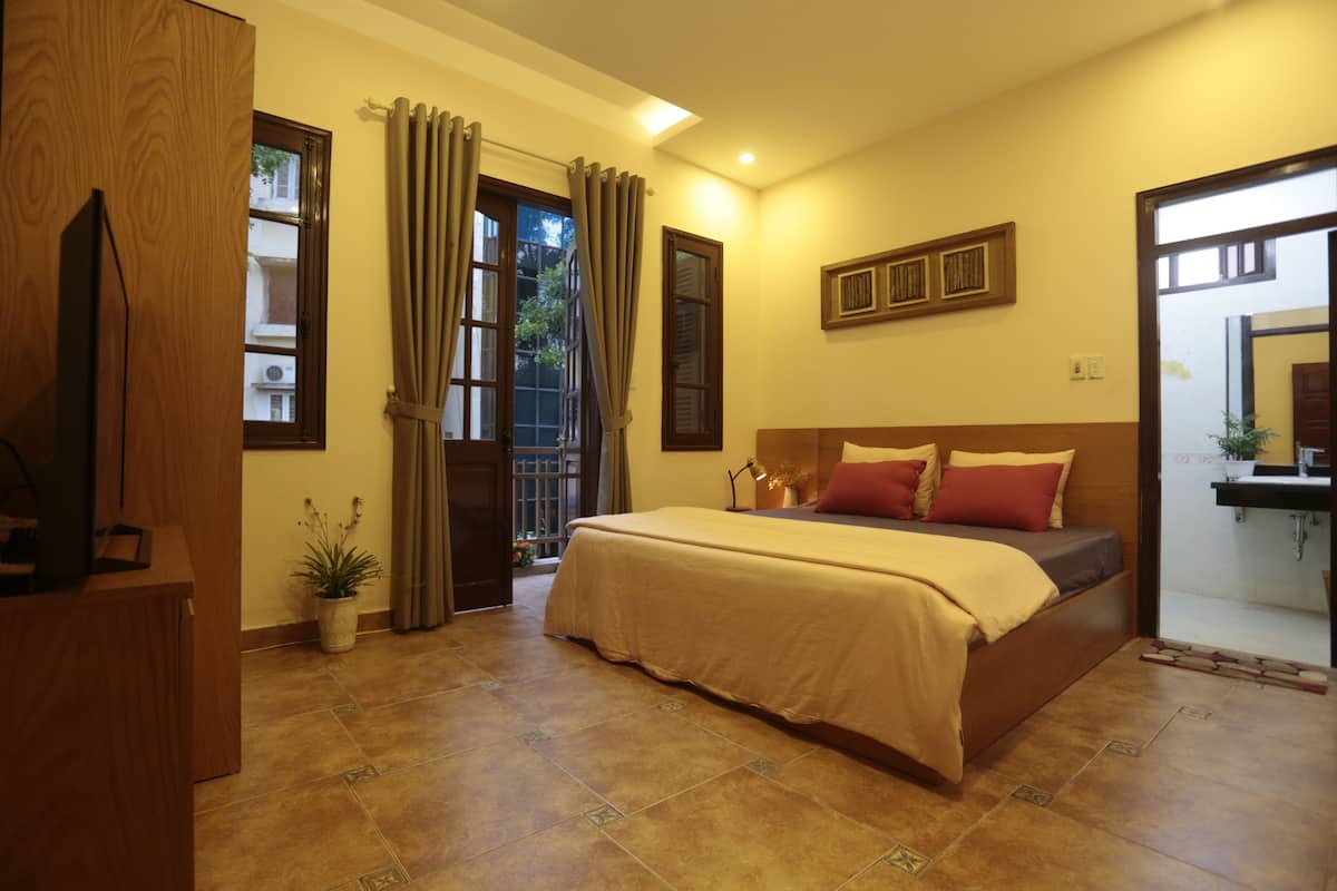 Un dormitorio con cama, cortinas, un escritorio y una planta en maceta.