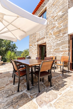 An outdoor dining area with stone flooring, wooden tables, and chairs.