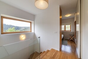 A modern interior with a staircase, a window with a view, and a hallway leading to a bedroom. - Private Villa with a Natural Pool Next to the Douro River (Gondomar)